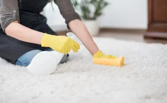 Limpieza de una alfombra con guantes amarillos en una vivienda de Barakaldo