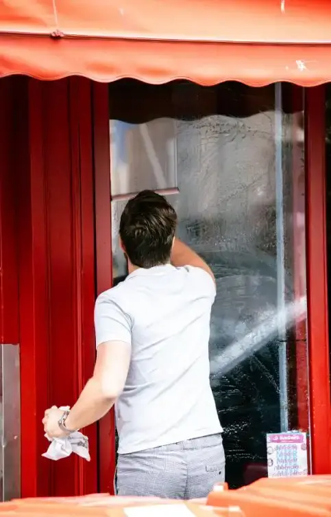Operario limpiando la fachada y la puerta exterior de un local en Barakaldo